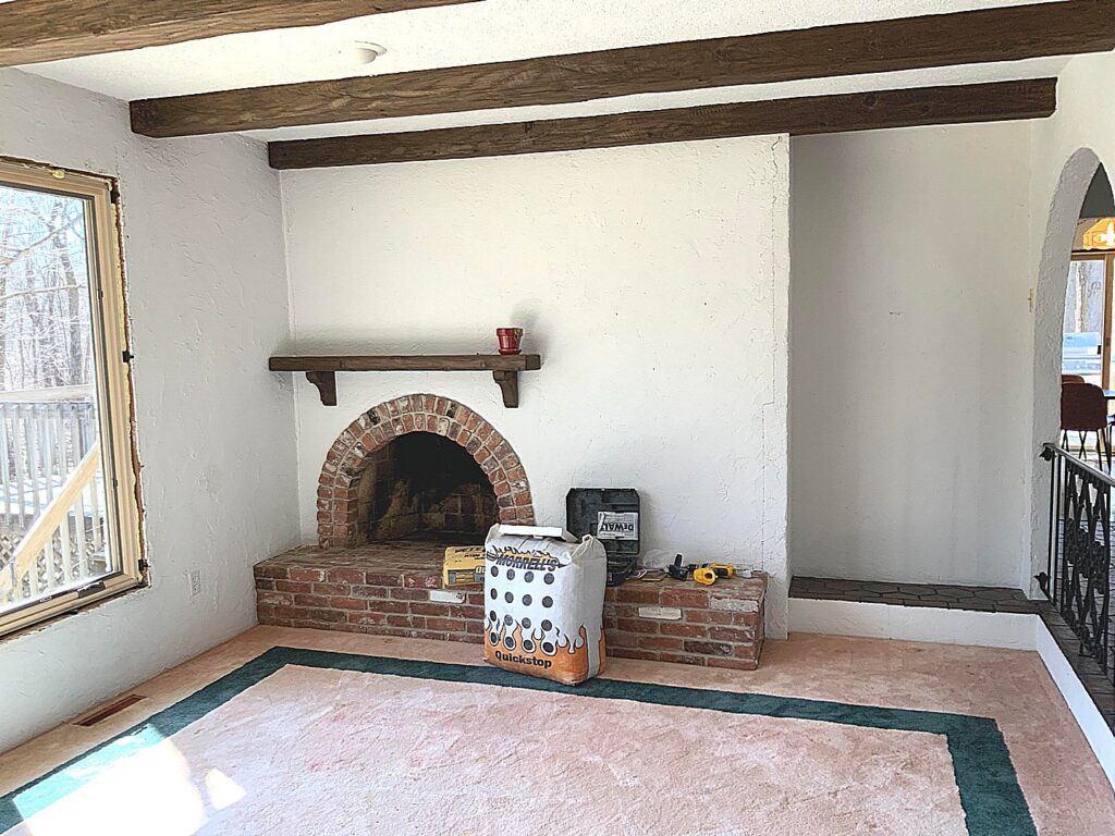 Old southwest style fireplace in sunken living room over carpet-covered plywood floor
