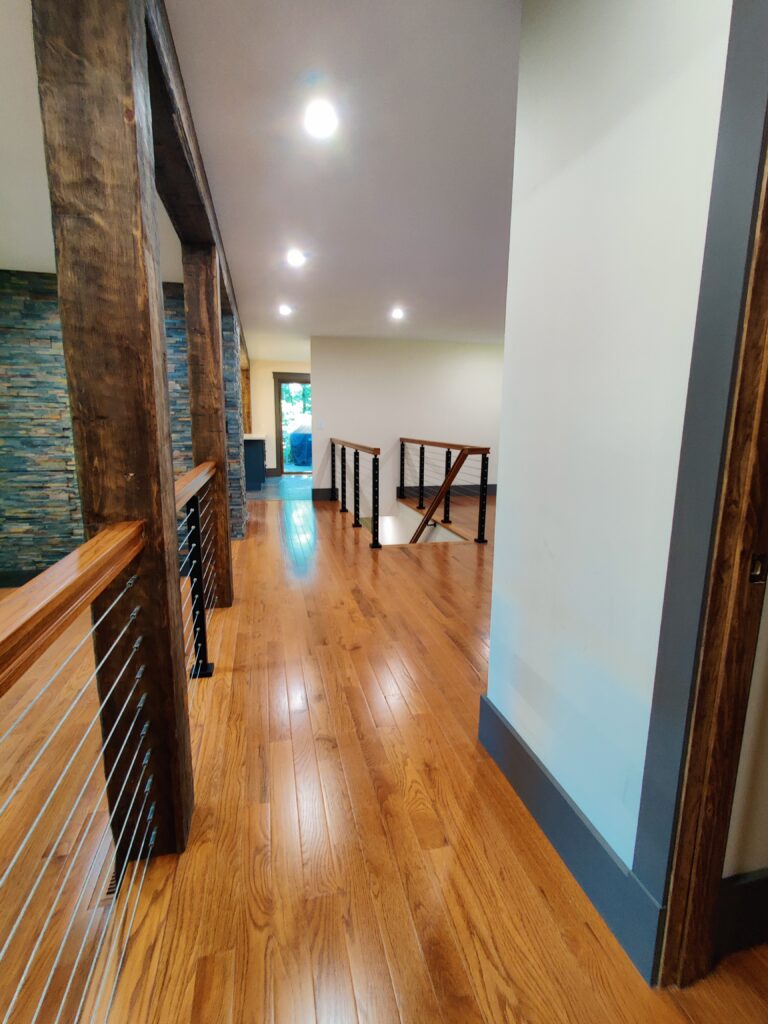 Hallway with custom oak rails with stainless steel cable railing over solid oak flooring